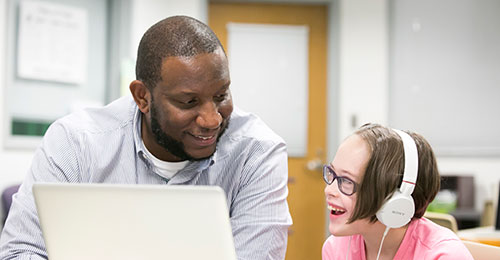 A paraeducator working with a student at the computer.