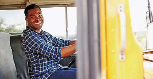 stock photo of male bus driver sitting and smiling in the driver seat