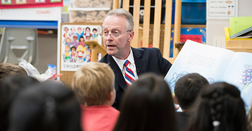Dr. Martirano reading a book to elementary school students