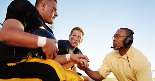 A coach speaking to football players.