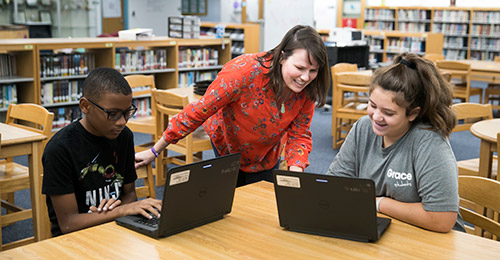 Lora Koehler working with students on laptops.