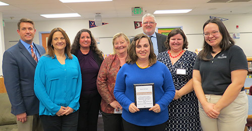 Partnership signing group holding plaque.