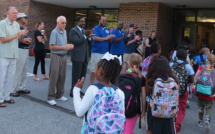 HCPSS partners clapping and celebrating BWES students as they enter the school building.