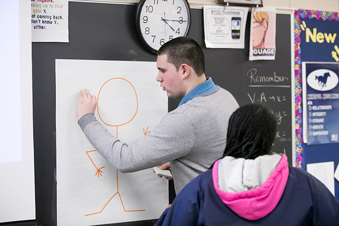 A male high school attendee marking a collaborative document with post-it notes.