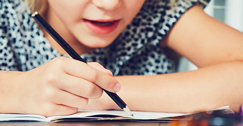 A close-up of a young female student working through a written test.