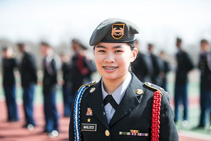 A female ROTC student is standing in front of a group of people.