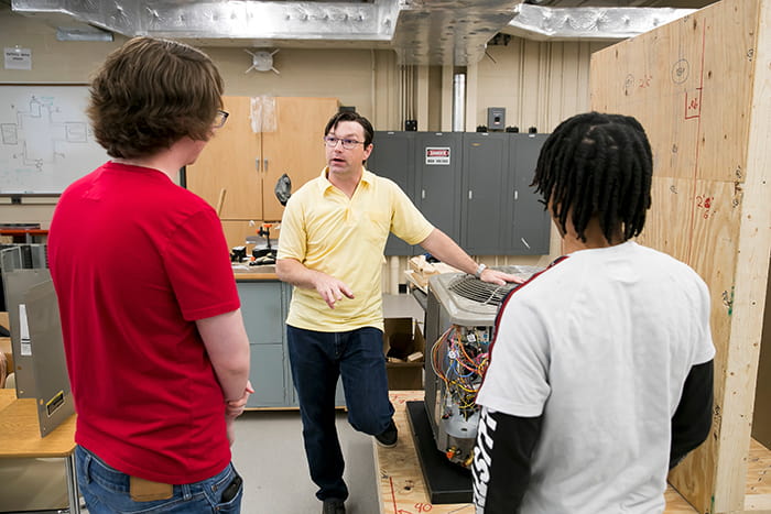 Keith Artley talking teaching two students about the different components of a HVAC system.