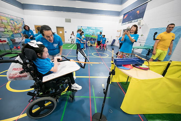A young female student in a wheelchair works with a teacher to learn an adapted game.