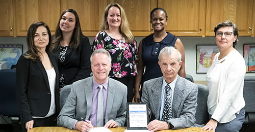 HCPSS Superintendent Matirano, several HCPSS staff, and representatives from the Italian Embassy hold a plaque commemorating their partnership.