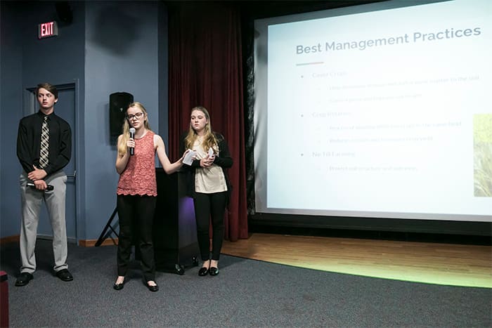 Three students deliver a PowerPoint presentation.