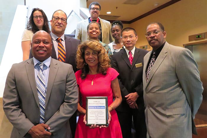 HCPSS Board of Education members and ational Society of Black Engineers, Jr. members stand on a staircase.