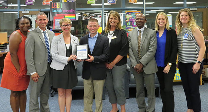 HCPSS staff and representatives from Comcast hold a plaque commemorating a new partnership.