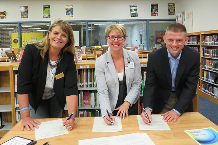 HCPSS and Comcast representatives sign a partnership agreement.