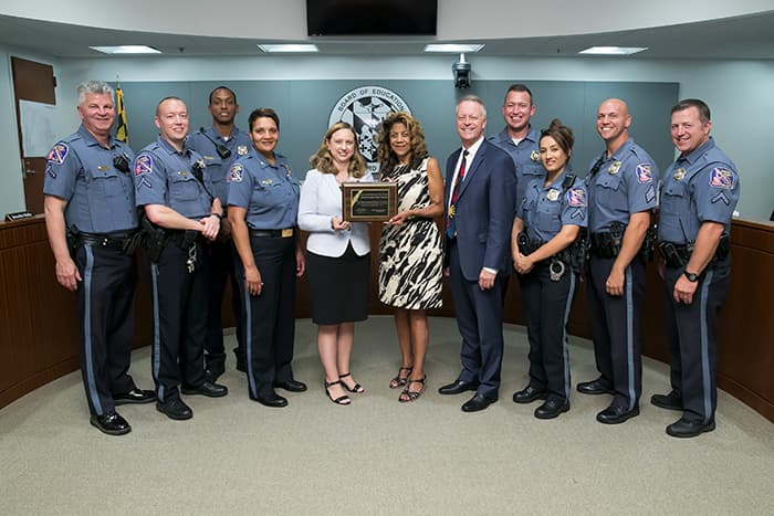 HCPSS Board Chair, Superintendent, and law enforcement officers hold a plaque.