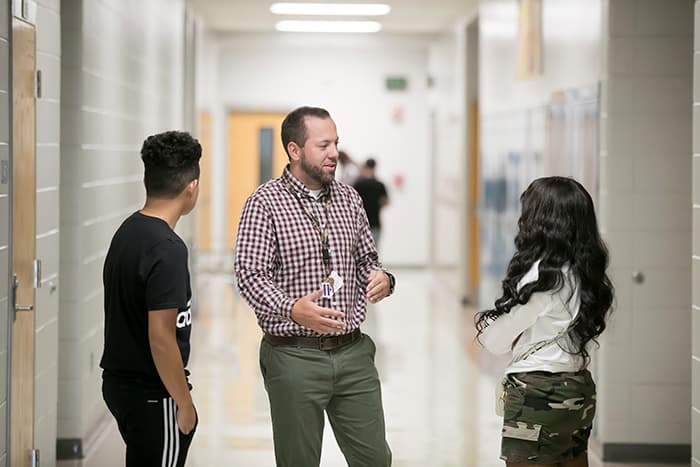 Kenny Porritt speaking with two students.