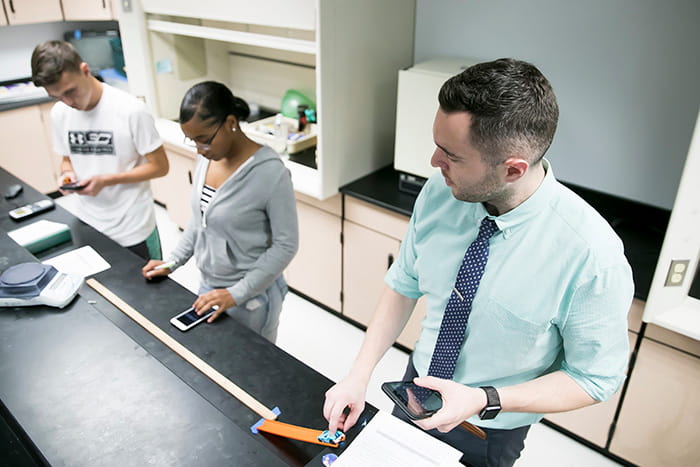 David Klotz in a lab with two students.