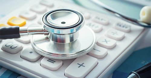 A stethoscope is lying on top of a calculator.