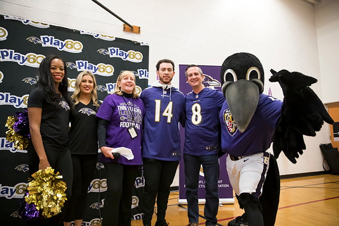 A Ravens player, cheerleaders, the Ravens mascot, and GES admininstrators.