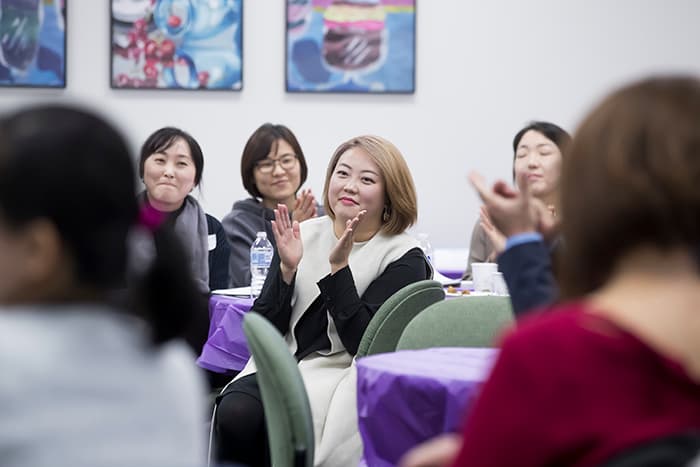 Group of women sitting down and clapping.