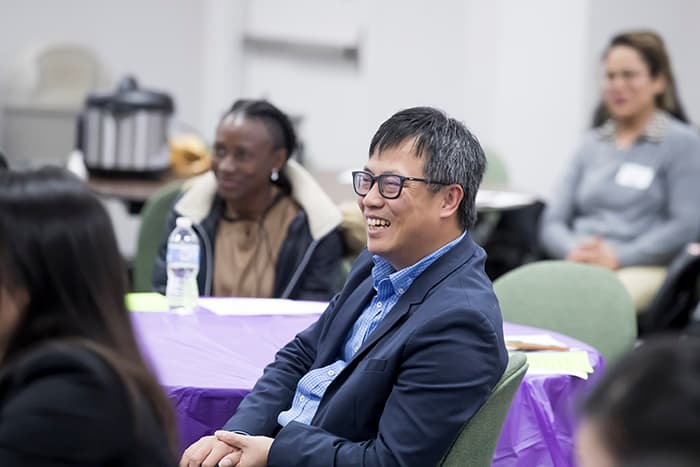 An Asian man smiling at an event.