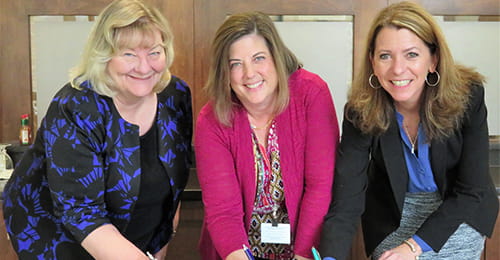 Three women signing a document.