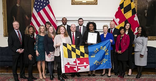 Representatives from MSDE, HCPSS, MVMS, and Annapolis hold a Blue Ribbon Banner.
