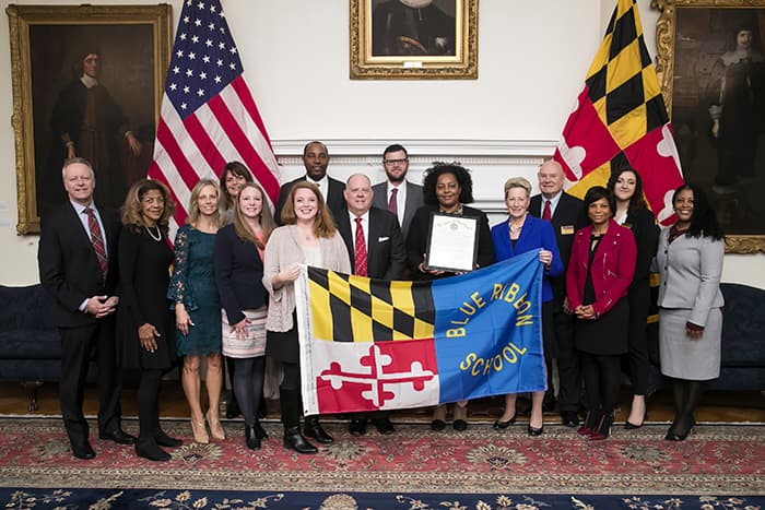 Representatives from HCPSS, Mount View Middle School, MSDE, and the Governor hold a "Blue Ribbon School" banner.