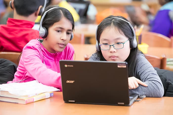 Two young female students looking at a laptop.