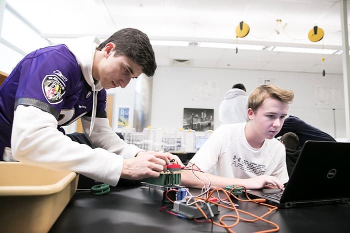 Two male students working on computer assembly and programming.