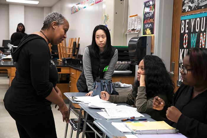 Female HCPSS teacher speaks to students while female South Korean teacher listens.