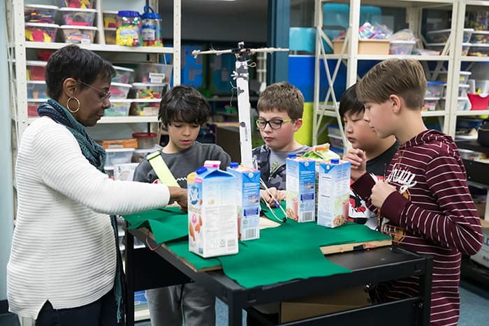 A teacher leads a group of male students in an experiment.