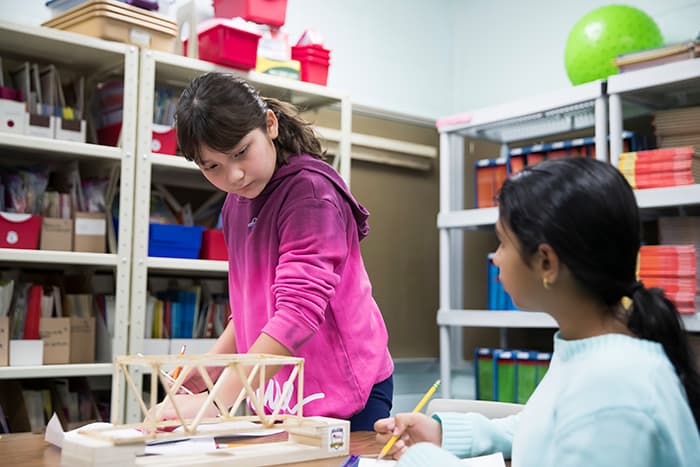 Two young girls working on an engineering project.