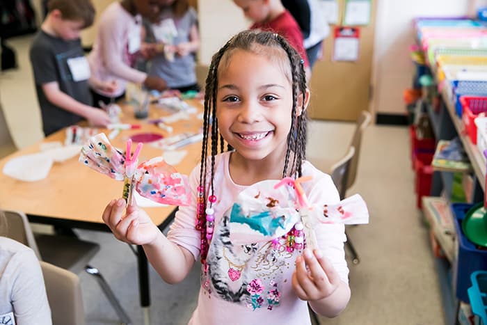 A young African American girl holds a craft she made.