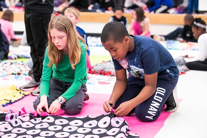 A male and a female student making a blanket.