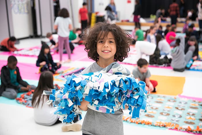 A male student holding a blanket he made.