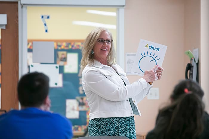 A teacher holds a flyer and talks to a student.