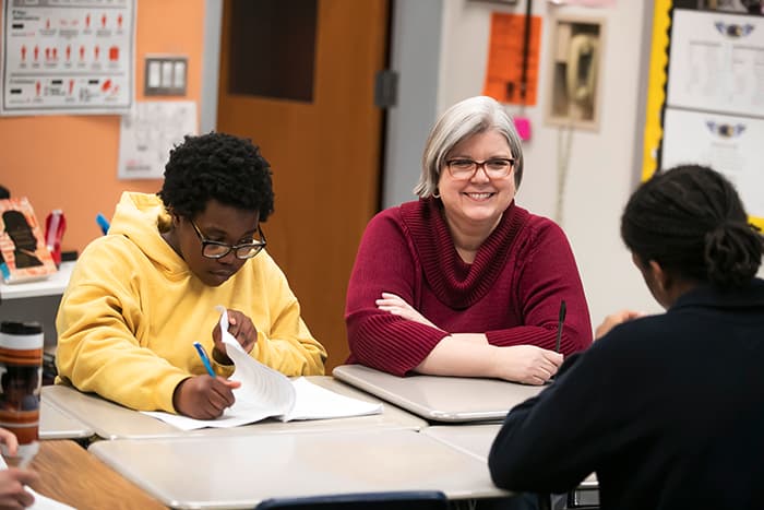 Diane Curry working at a table with students.