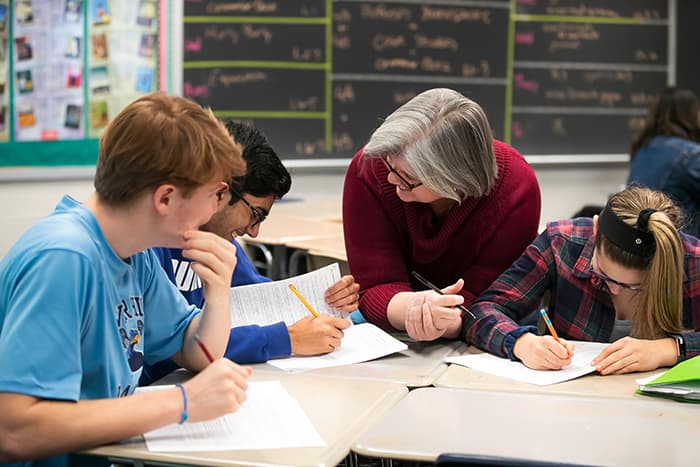 Diane Curry working at a table with students.