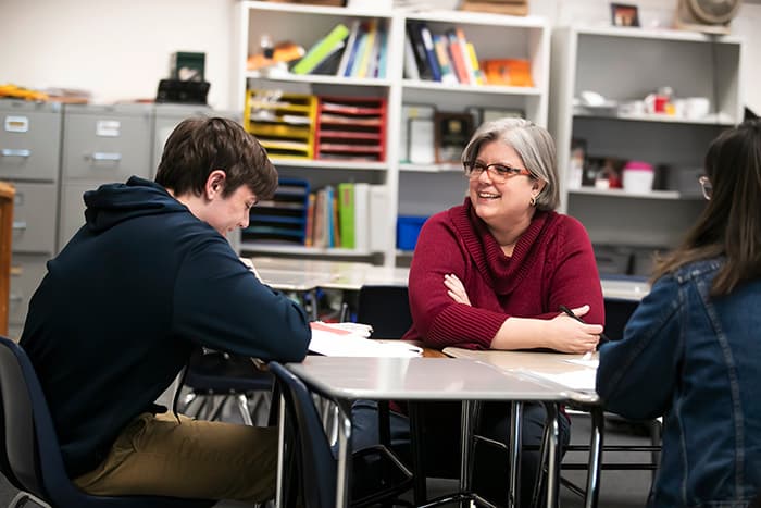 Diane Curry working at a table with students.