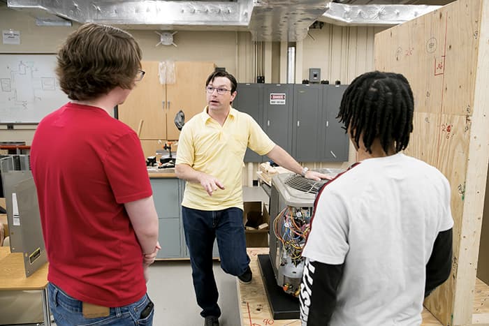 Keith Artley talks to two students in a lab.