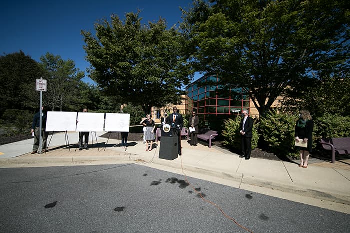 Calvin Ball speaking and standing with a group outside of a school.