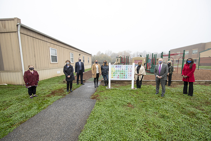 Group of people standing in front of new playground sign at WAVES.