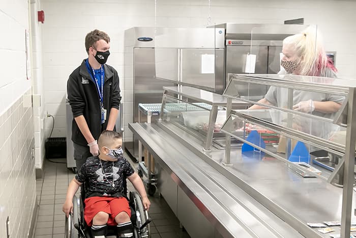 Bradley Wilson in the cafeteria with a student in a wheelchair.