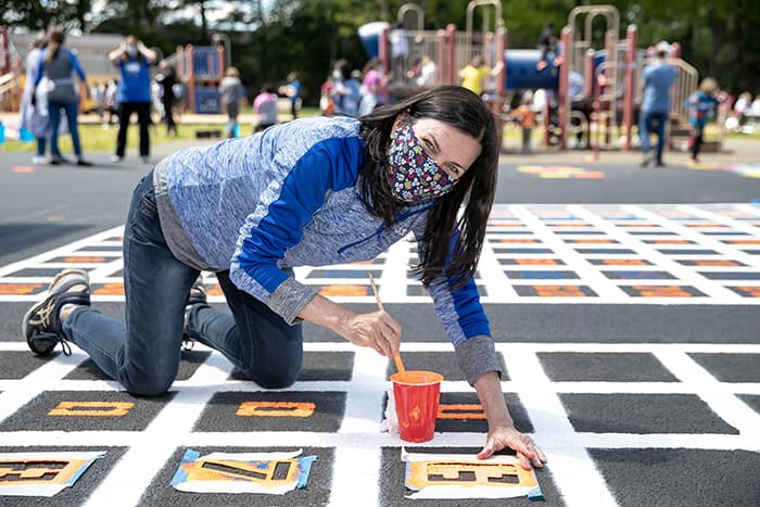 Kathleen Miller painting on a sidewalk.