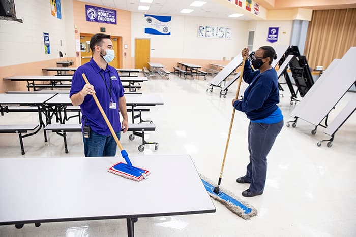 Joshua Simmons and his colleague clean the Mount View Middle School cafeteria.