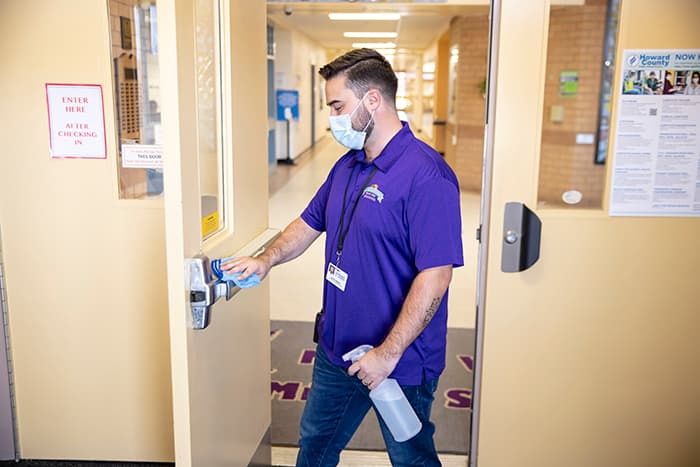 Joshua Simmons cleaning door handles at Mount View Middle School.