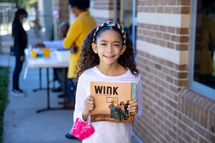 Female LOES student holding the book Wink.