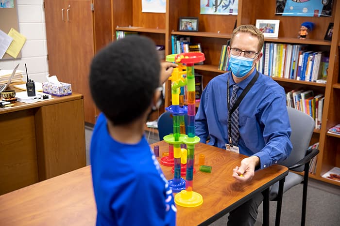 HHES School Pyschologist Jeff Leard working with a male student.