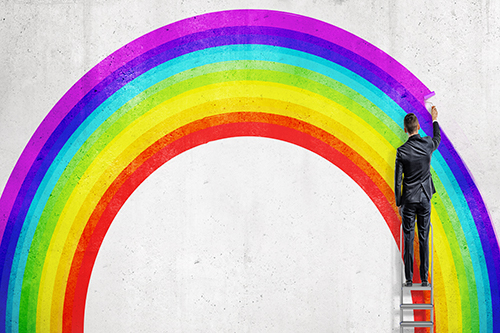 A businessman stands on a stepladder and drawing the last colorful line in the wall picture of a rainbow. 