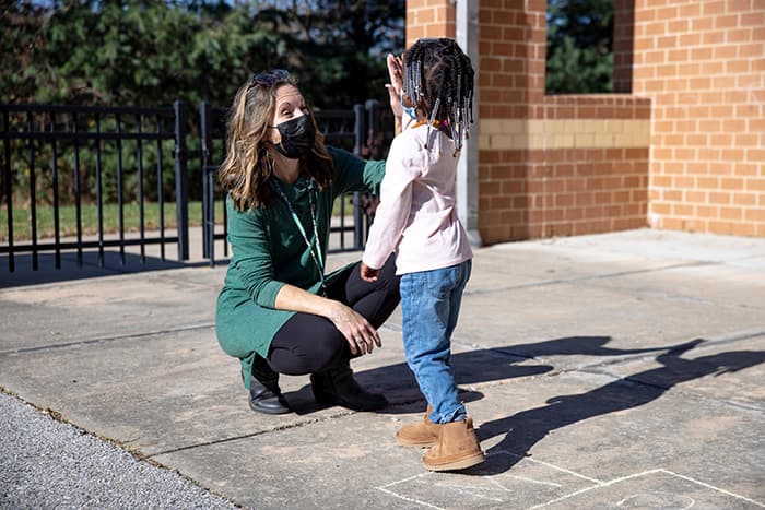 VES Pre-K teacher Lea Clink gives her student a high-five on the playground.